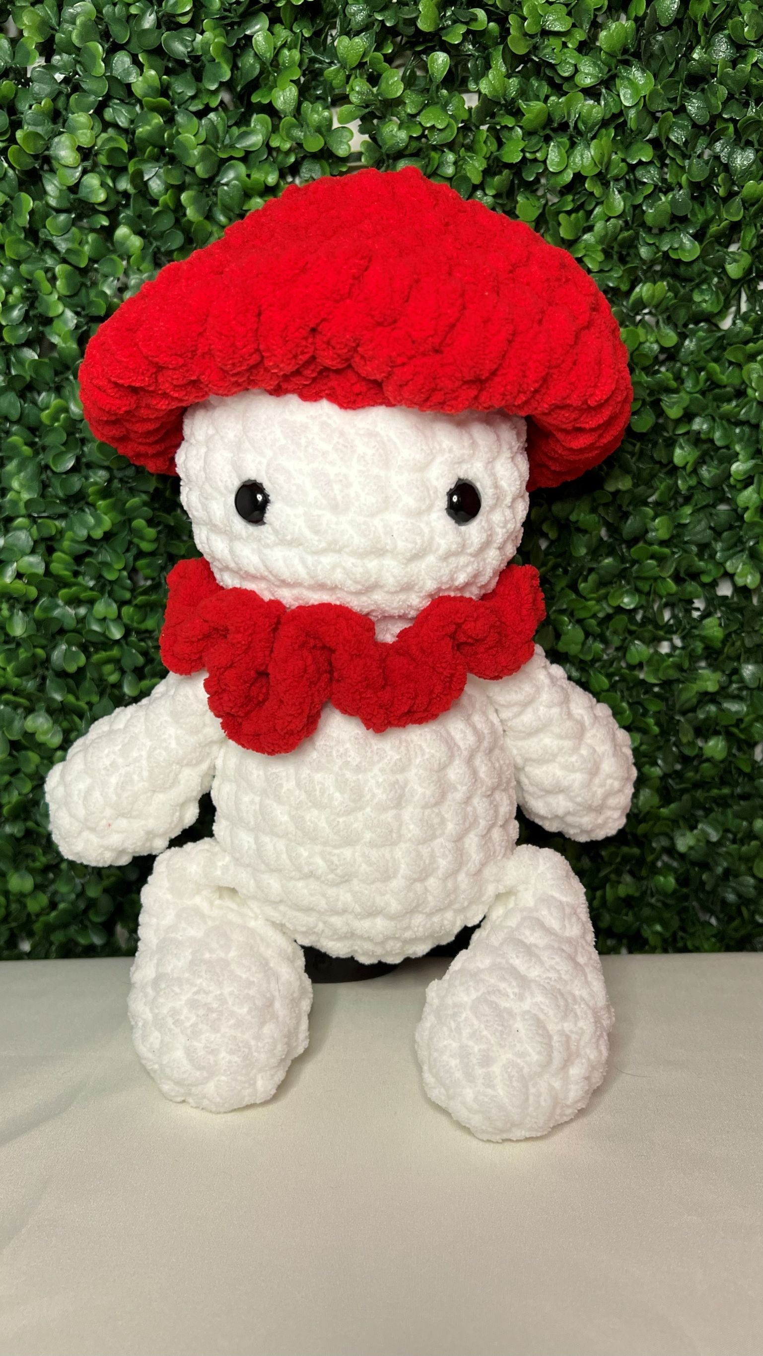 Crocheted mushroom plush toy with a red cap and scarf 